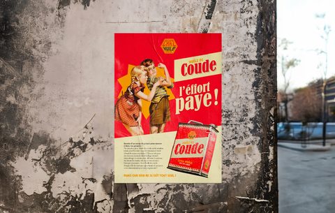 Affiche rétro Huile de Coude « L’effort paye ! » collée sur un mur en béton.